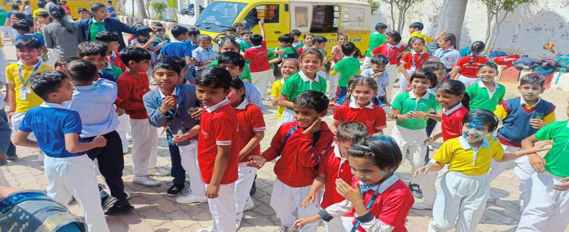 Students in red, green, yellow and blue house T-shirts in the courtyard
